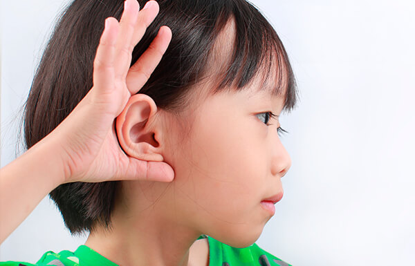 Niño mostrando su orejas tras postoperatorio de otoplastia